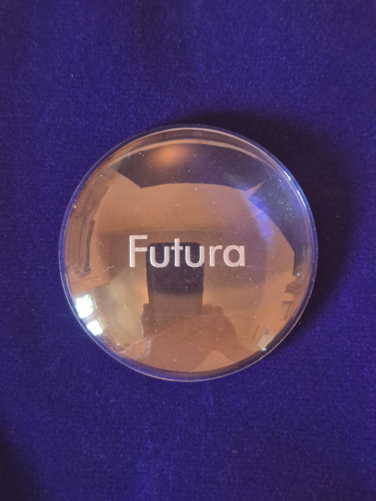 round glass disk on blue background with the word Futura engraved in middle