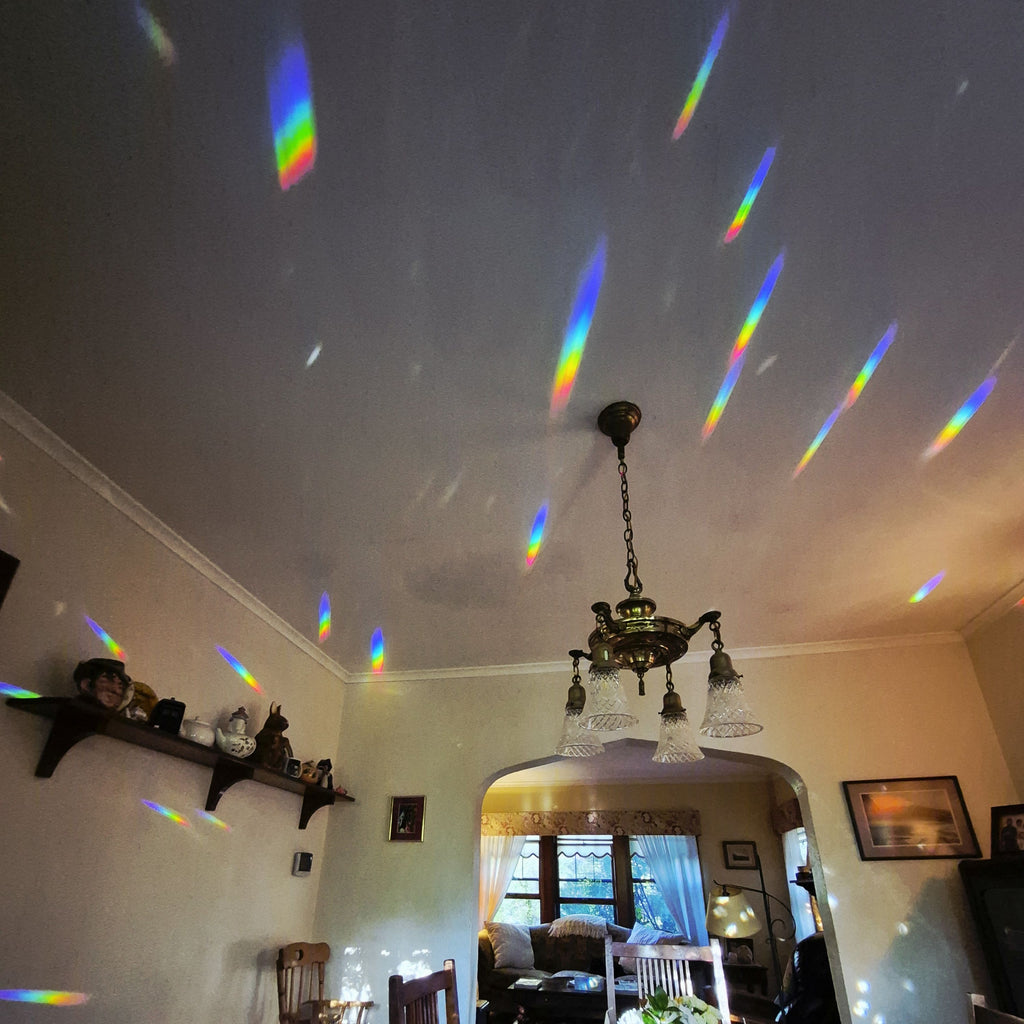 a spectacular scene of vivid brilliant rainbow confetti projected onto ceiling and walls from a lead crystal prism suncatcher in the adjacent window