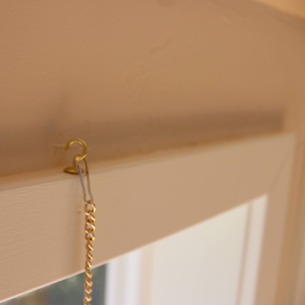 teacup hook screwed into window trim with lanyard hook and gold chain attached