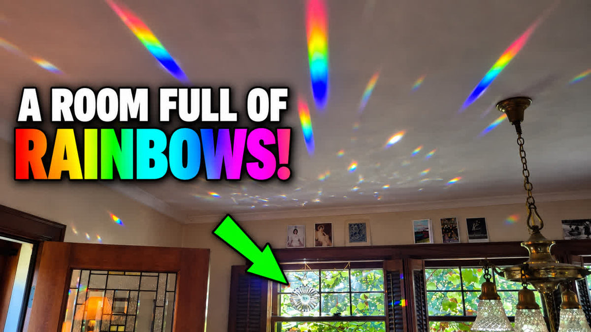A room interior with rainbow light beams projected across the ceiling and walls, large text reading 'A ROOM FULL OF RAINBOWS!', a green arrow pointing to a prism suncatcher in the window, and a hanging chandelier visible.
