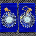 two iridescent filled centers of 6-inch prism suncatchers lying on blue velvet in the afternoon sun
