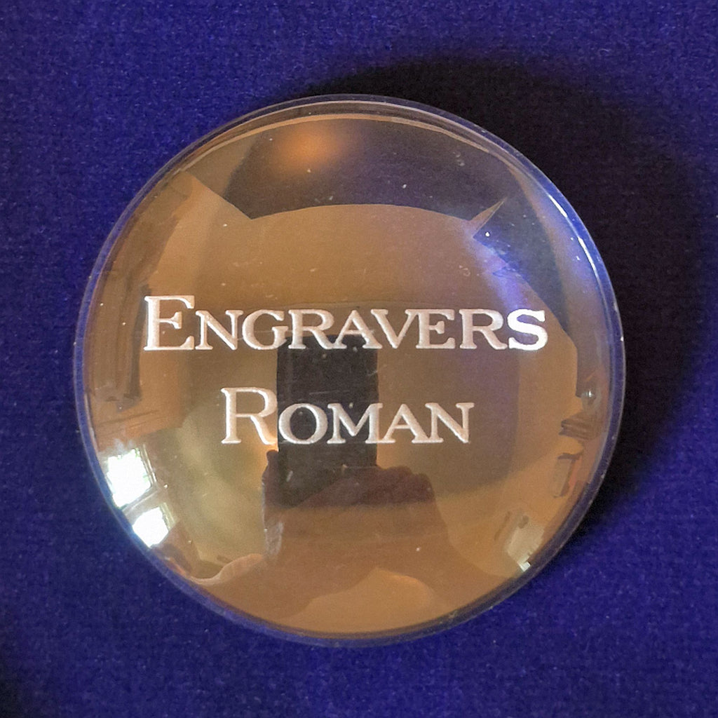 glass disk with sample of ENGRAVERS ROMAN marked in center