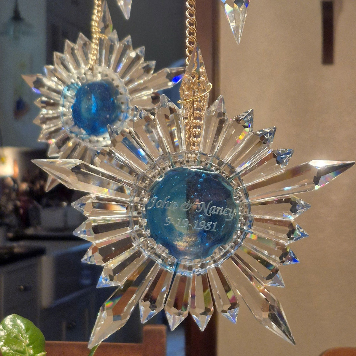 two star shaped prism suncatchers with names and wedding date engraved hanging from a dining room chandelier