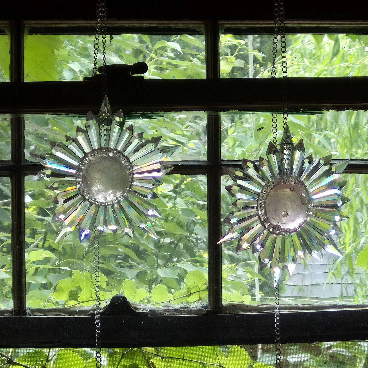 two pink bubble designs over center of star-shaped prism suncatchers hanging in a divided glass wood frame window