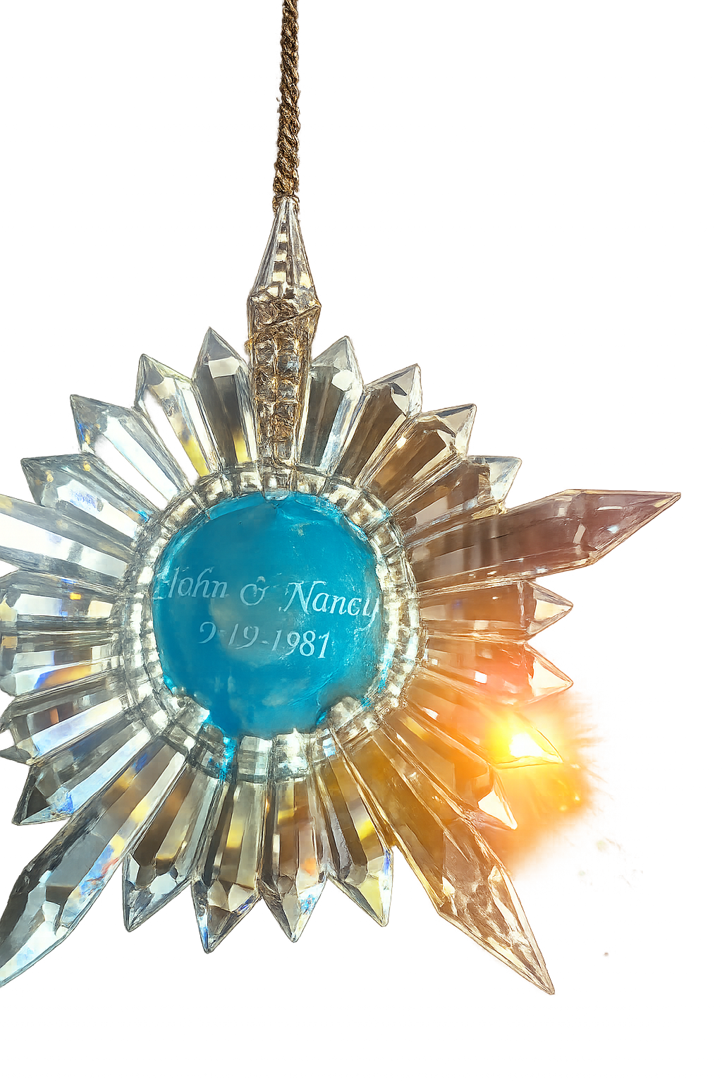 A personalized clear crystal sunburst ornament with a central blue circle engraved with 'John & Nancy 9-19-1981