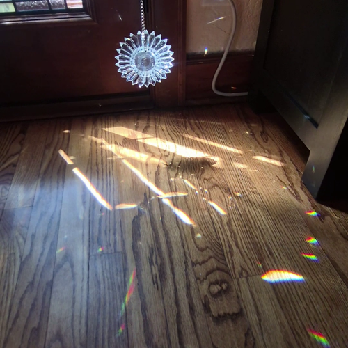 a 5-inch prism suncatcher held hanging in a patch of sunlight