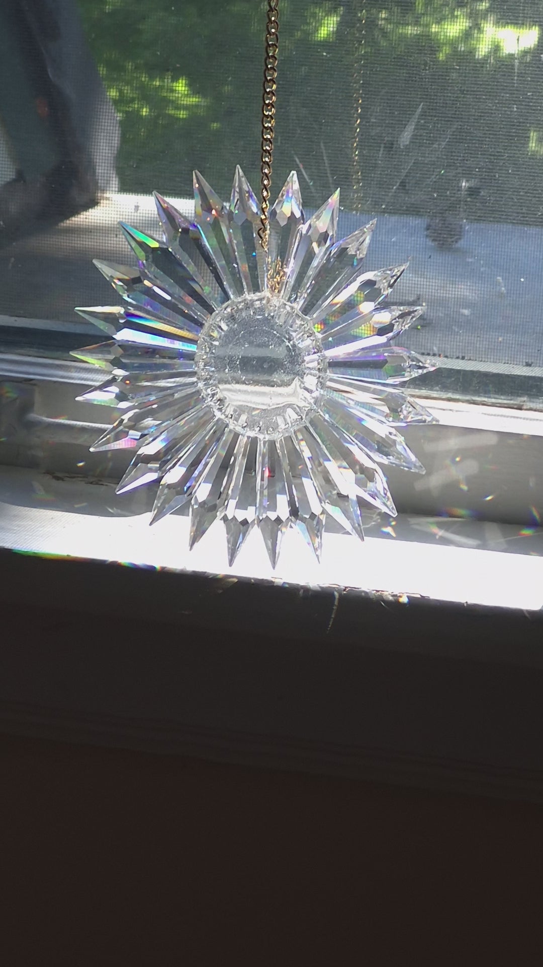 video of a prism suncatcher refracting sunlight onto adjacent walls, floor and door.